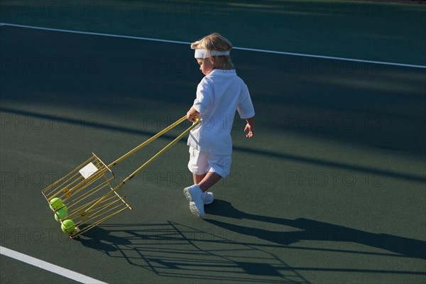 Boy (2-3) pulling basket with tennis balls