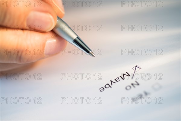 Close-up of hand filling out form.