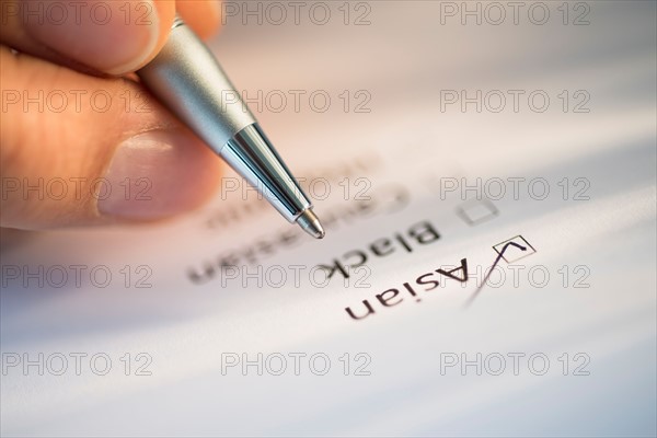 Close-up of hand filling out form.