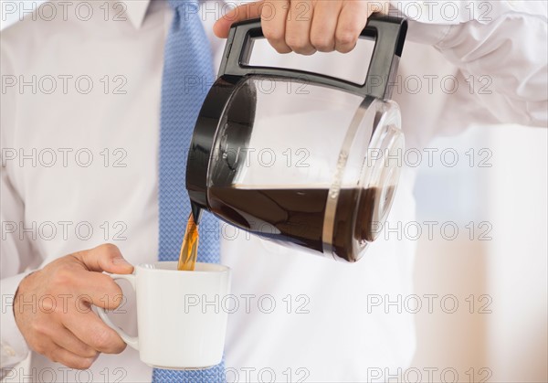 Businessman pouring coffee.