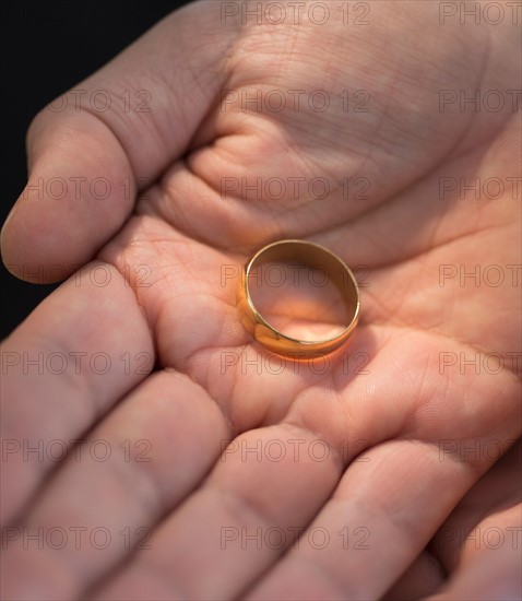 Hand holding wedding ring.