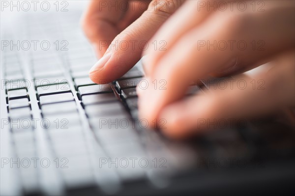 Close-up of hands typing on keyboard.