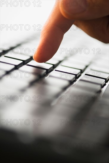 Close-up of finger typing on keyboard.