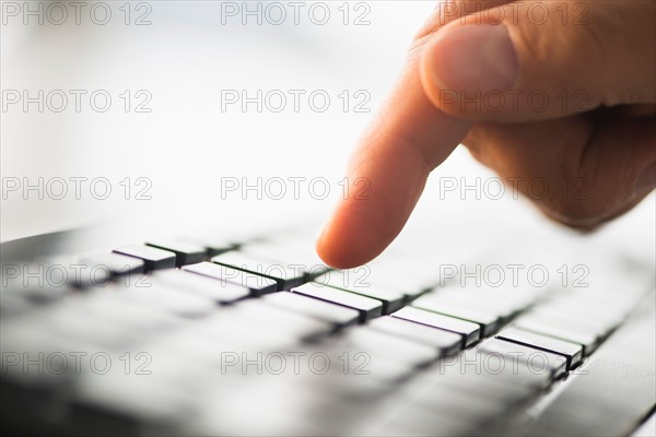 Close-up of finger typing on keyboard.