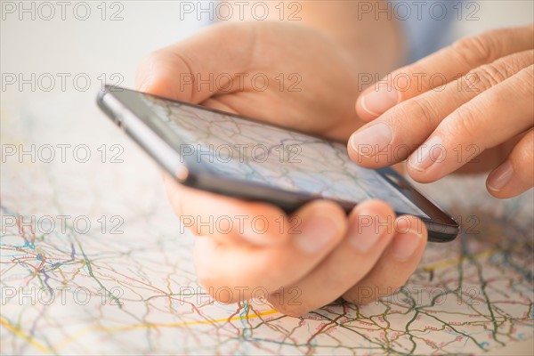 Close-up of hand using smartphone over map.