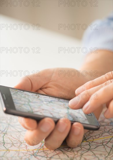 Close-up of hand using smartphone over map.