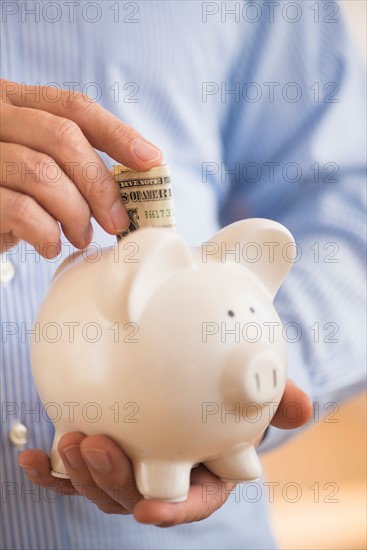 Man inserting money into piggy bank.