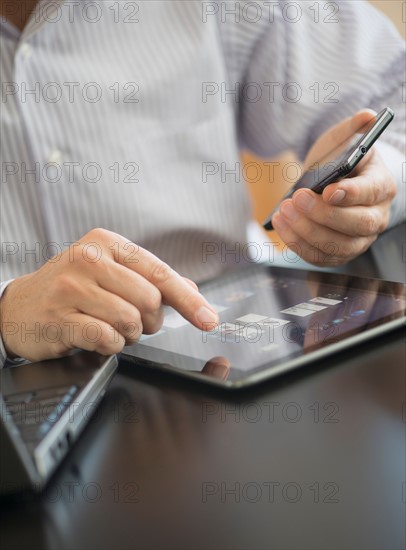 Man using tablet pc, laptop and smartphone.