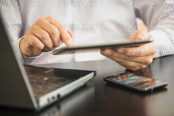 Man using tablet pc, laptop and smartphone.