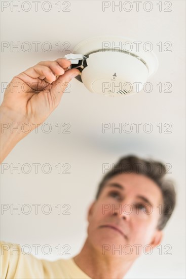 Man changing battery in smoke alarm.