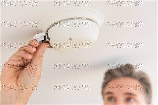 Man changing battery in smoke alarm.