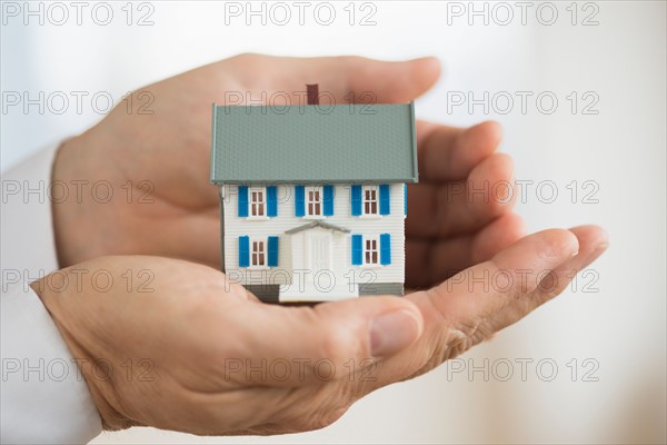 Hands holding model house.