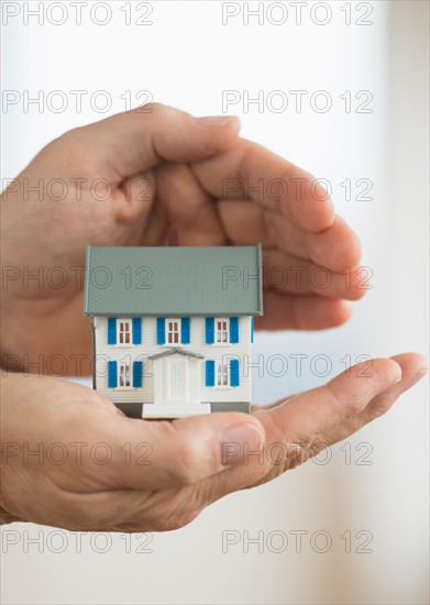 Hands holding model house.