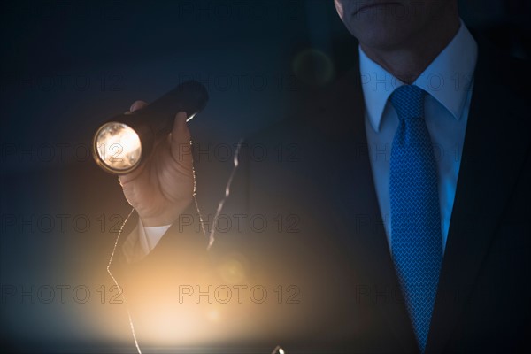 Businessman holding flashlight.