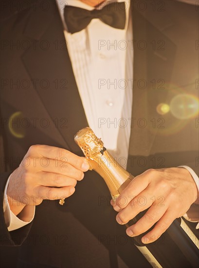 Elegant man opening champagne.