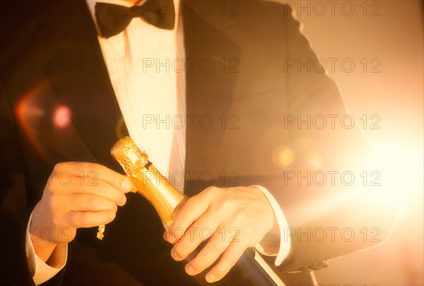 Elegant man opening champagne.