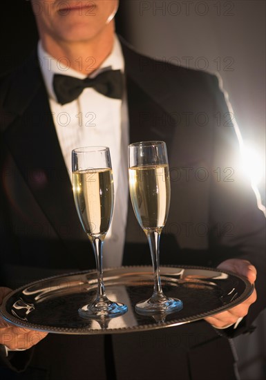 Waiter holding tray with champagne.