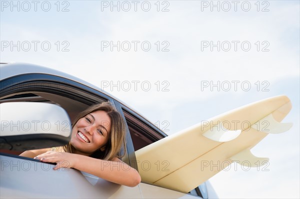 Woman driving car with surfboard inside. Photo : Jamie Grill