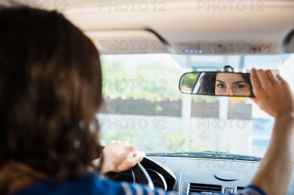 Woman adjusting rear view mirror in car. Photo : Jamie Grill