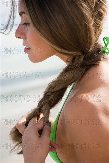 Beautiful woman braiding hair at beach. Photo : Jamie Grill