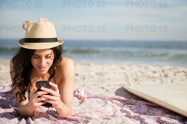 Woman using cell phone on beach. Photo : Jamie Grill