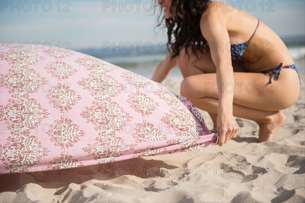 Woman preparing blanket on beach. Photo : Jamie Grill