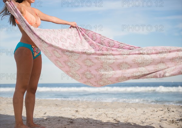 Woman preparing blanket on beach. Photo : Jamie Grill