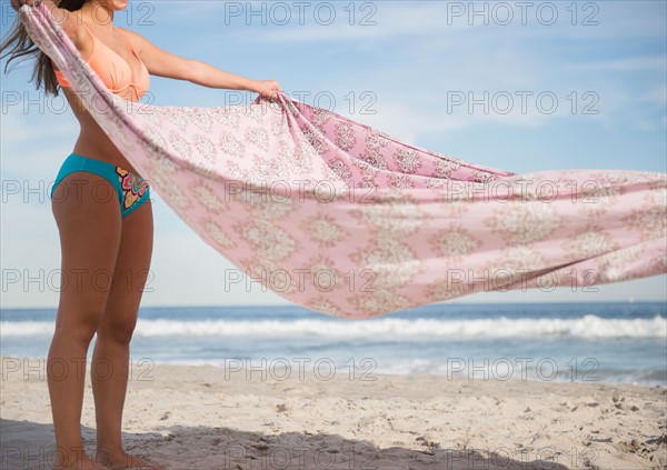 Woman preparing blanket on beach. Photo: Jamie Grill