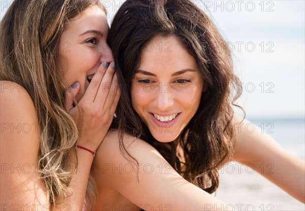 Two women whispering on beach. Photo : Jamie Grill