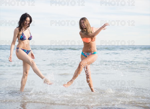 Two young women splashing water on beach. Photo: Jamie Grill