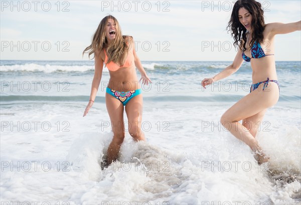 Two young women jumping in sea. Photo : Jamie Grill