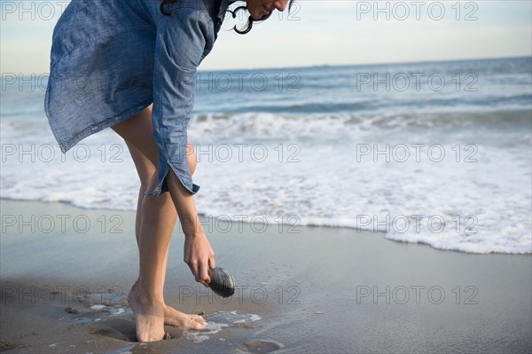 Woman collecting seashells on beach. Photo: Jamie Grill