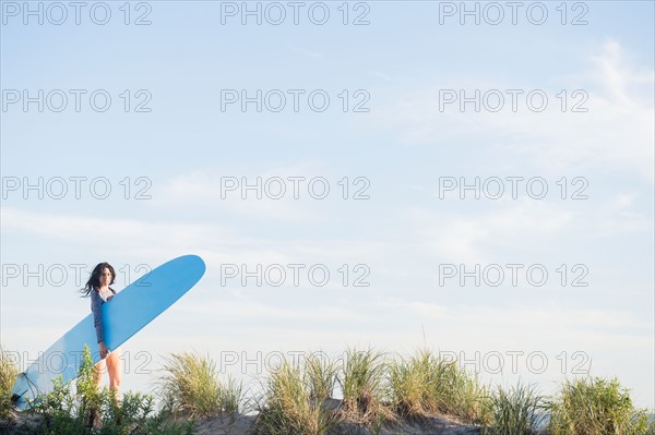 Female surfer walking on beach. Photo : Jamie Grill