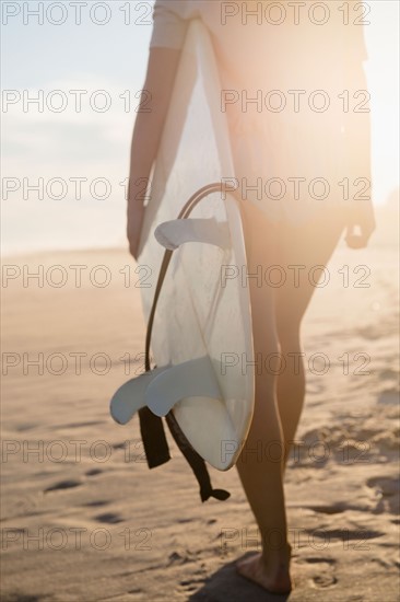 Female surfer walking on beach at sunset. Photo : Jamie Grill