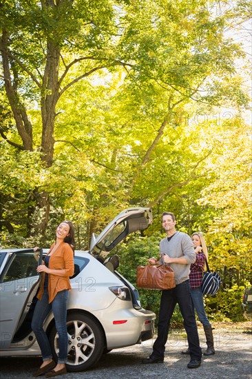 Three friends packing luggage into car. Photo: Jamie Grill