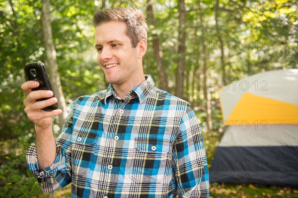 Man using cell phone in forest. Photo : Jamie Grill