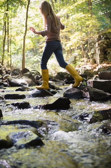 Woman walking on rocks in stream. Photo : Jamie Grill