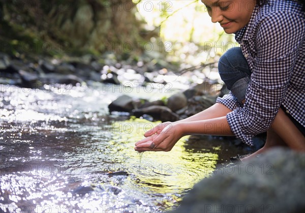 Woman crouching by stream. Photo : Jamie Grill