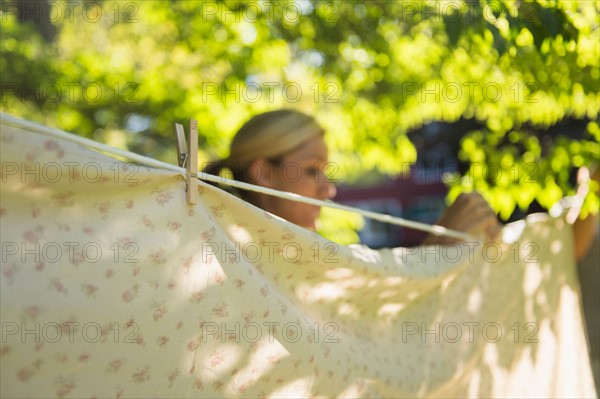 Woman hanging laundry on clothesline. Photo : Jamie Grill