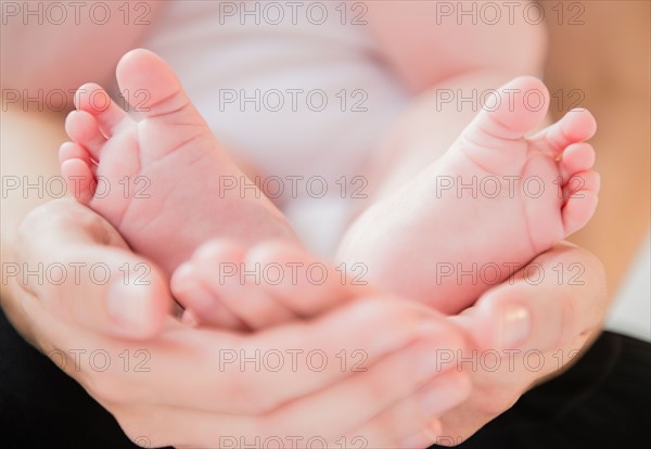 Mother holding feet of baby boy (2-5 months). Photo : Jamie Grill