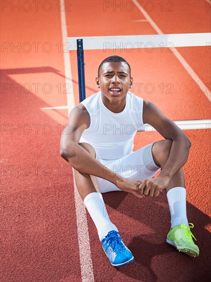 Portrait of boy (12-13) resting on running track.