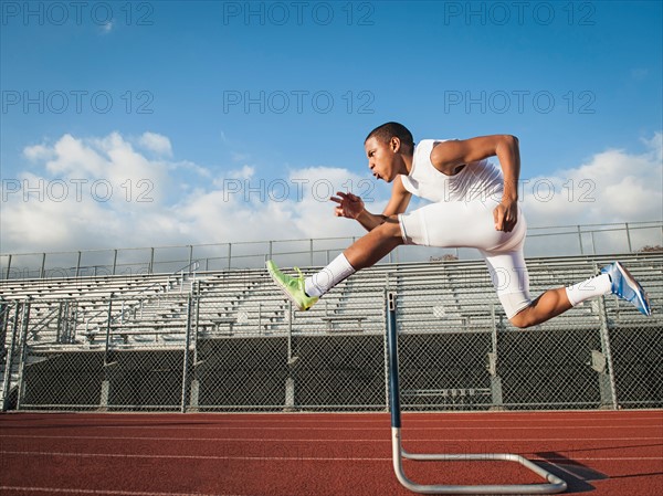 Boy (12-13) hurdling on running track. Photo: Erik Isakson