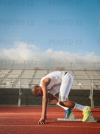 Boy (12-13) preparing for running on starting line.