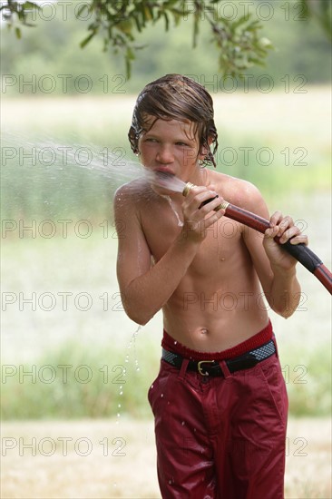 Boy (10-11) drinking from water hose in summer. Photo : pauline st.denis