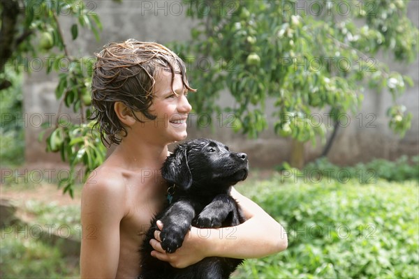 Boy (10-11) with Labrador puppy playing with water . Photo : pauline st.denis