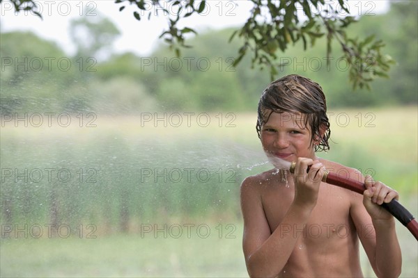 Boy (10-11) drinking from water hose in summer. Photo : pauline st.denis