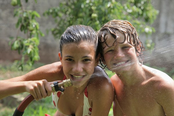 Boy (10-11) playing with water hose in summer. Photo : pauline st.denis