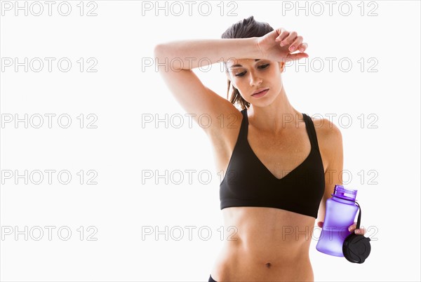 Young woman resting after exercising, studio shot. Photo : Mike Kemp