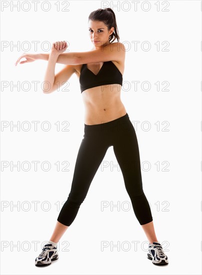 Young woman stretching, studio shot. Photo : Mike Kemp