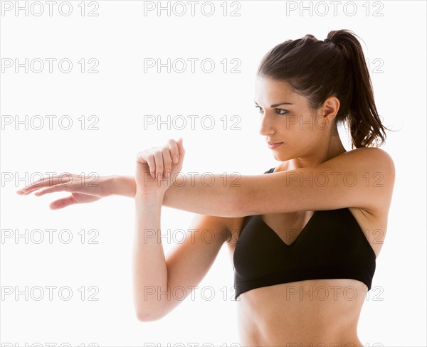 Young woman stretching, studio shot. Photo : Mike Kemp